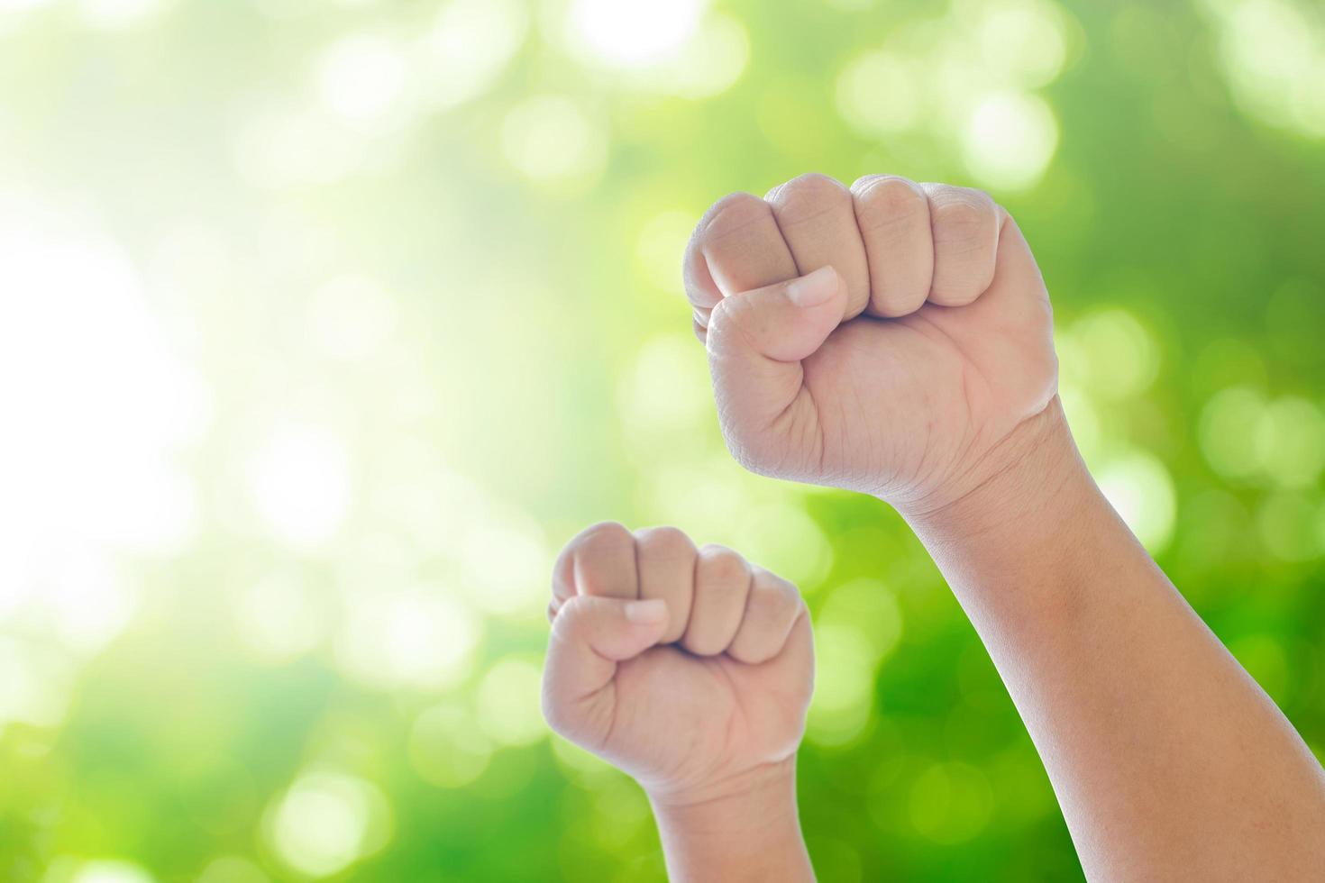 Fists on green natural bokeh background photo