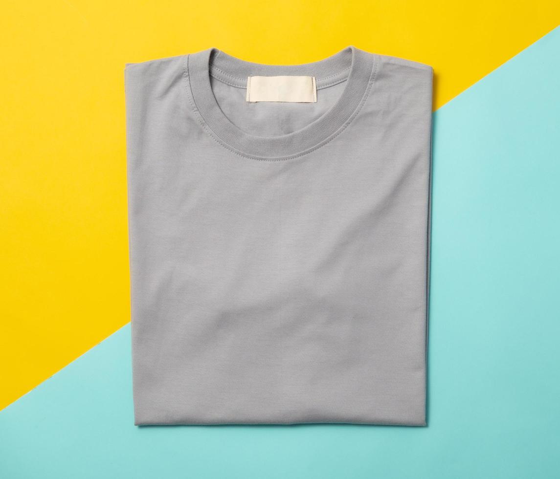 Grey folded t-shirt isolated on yellow and blue background photo