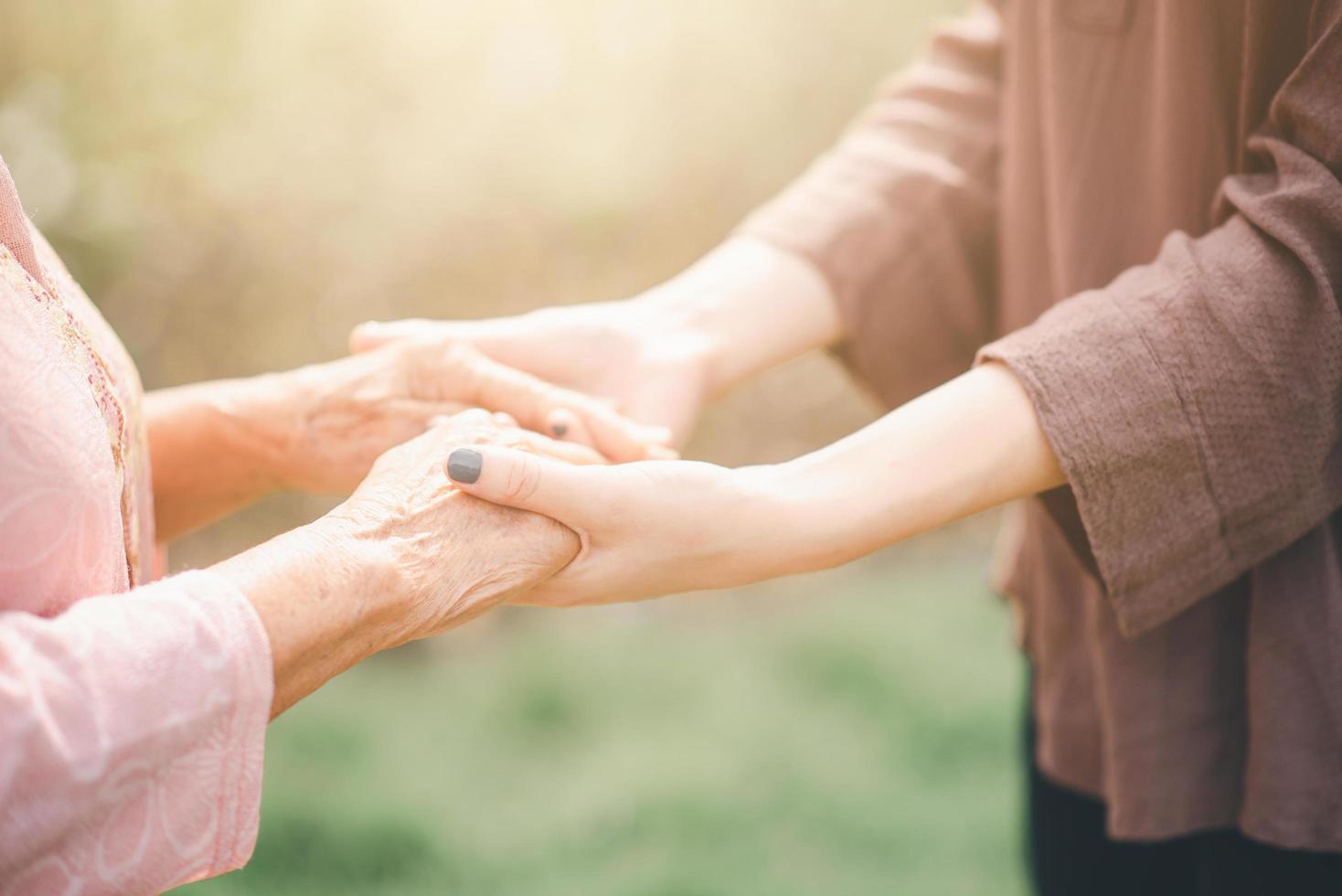 anciana y joven tomados de la mano foto