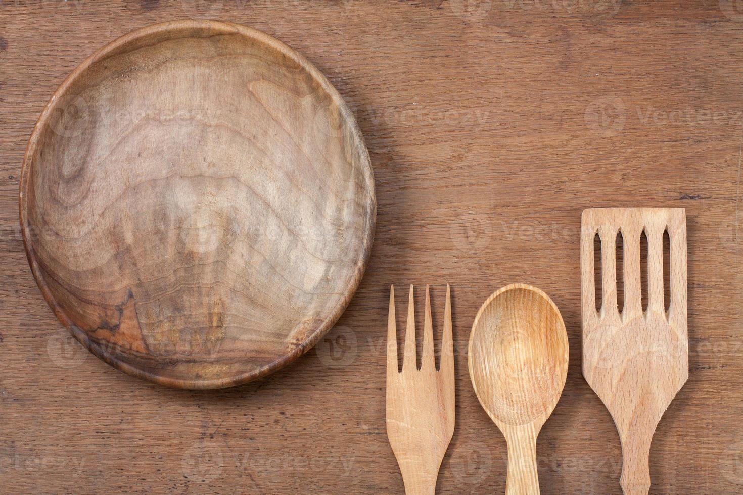 Wooden plate, fork and spoon on oak wood texture background photo
