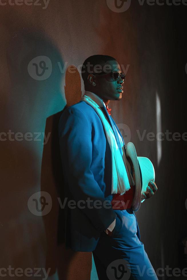 retro hombre afroamericano en traje azul con gafas de sol. foto