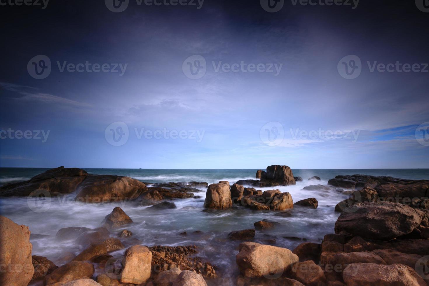 Waves crashing on rocky shore in the sunset photo