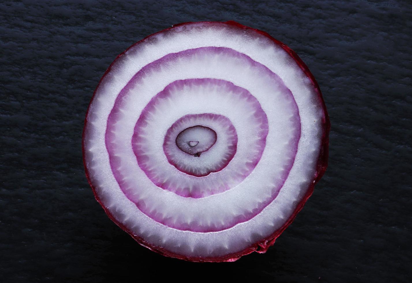 Cebolla roja cortada por la mitad sobre fondo de pizarra foto