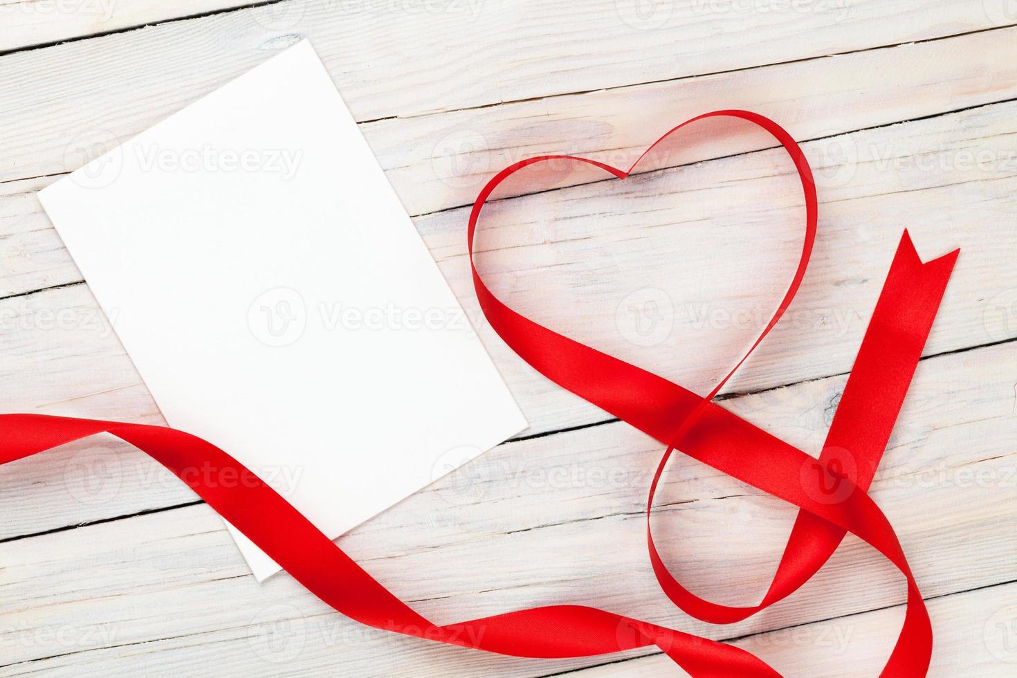 día de san valentín cinta roja en forma de corazón y tarjeta de felicitación en blanco foto