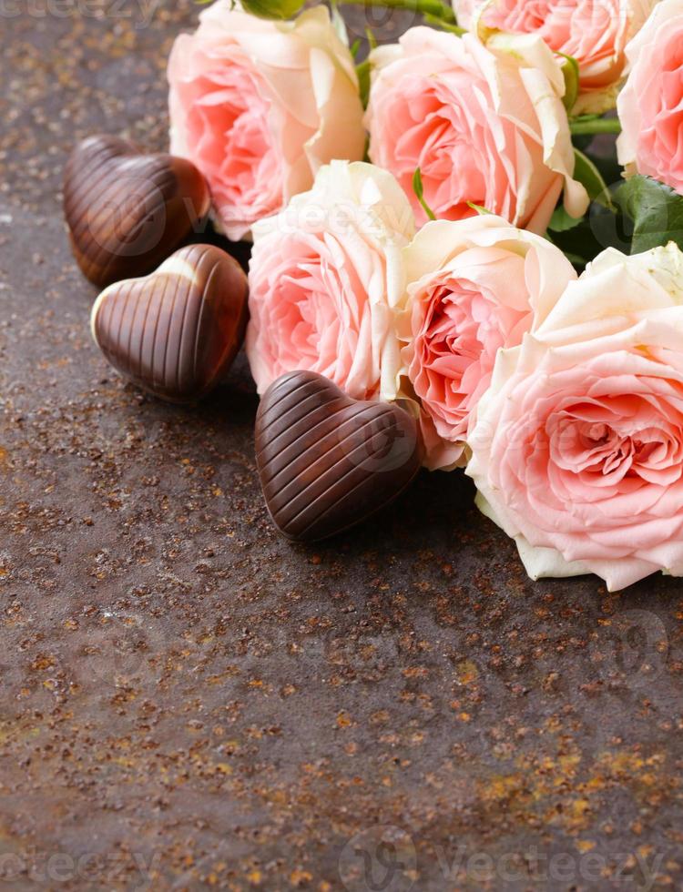 corazones de caramelo de chocolate y rosas rosadas foto