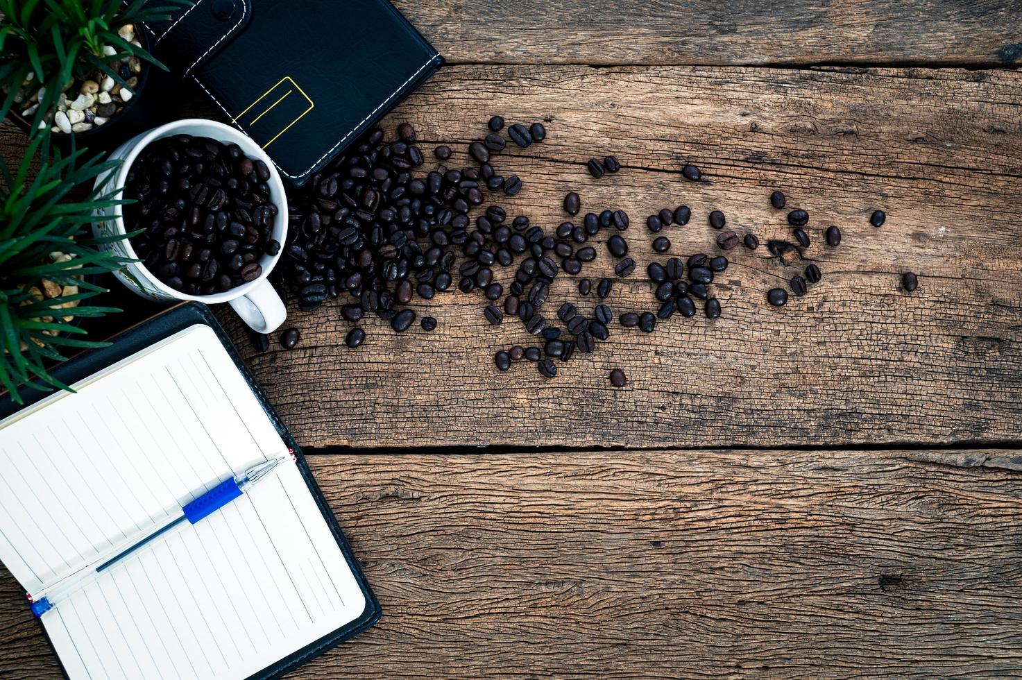 Cuadernos, bolígrafos y granos de café en el escritorio. foto