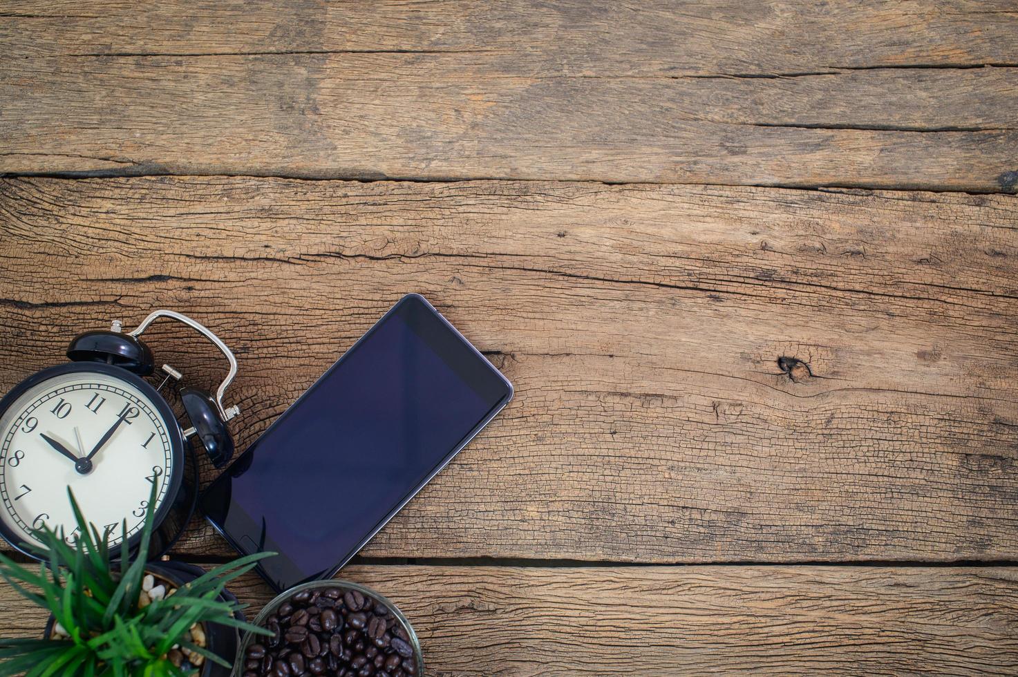 teléfono inteligente, reloj y granos de café en el escritorio foto