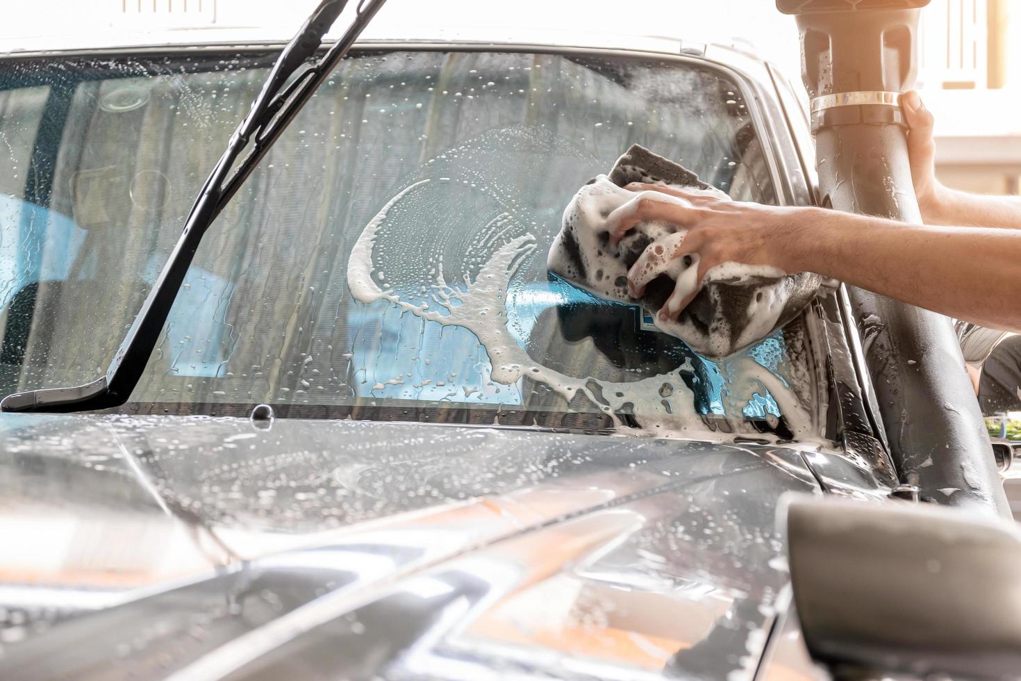 The car wash staff is using a sponge to clean the windshield  photo