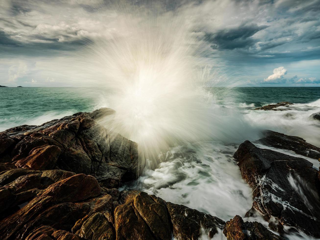 Smooth ocean wave with rock formation background  photo