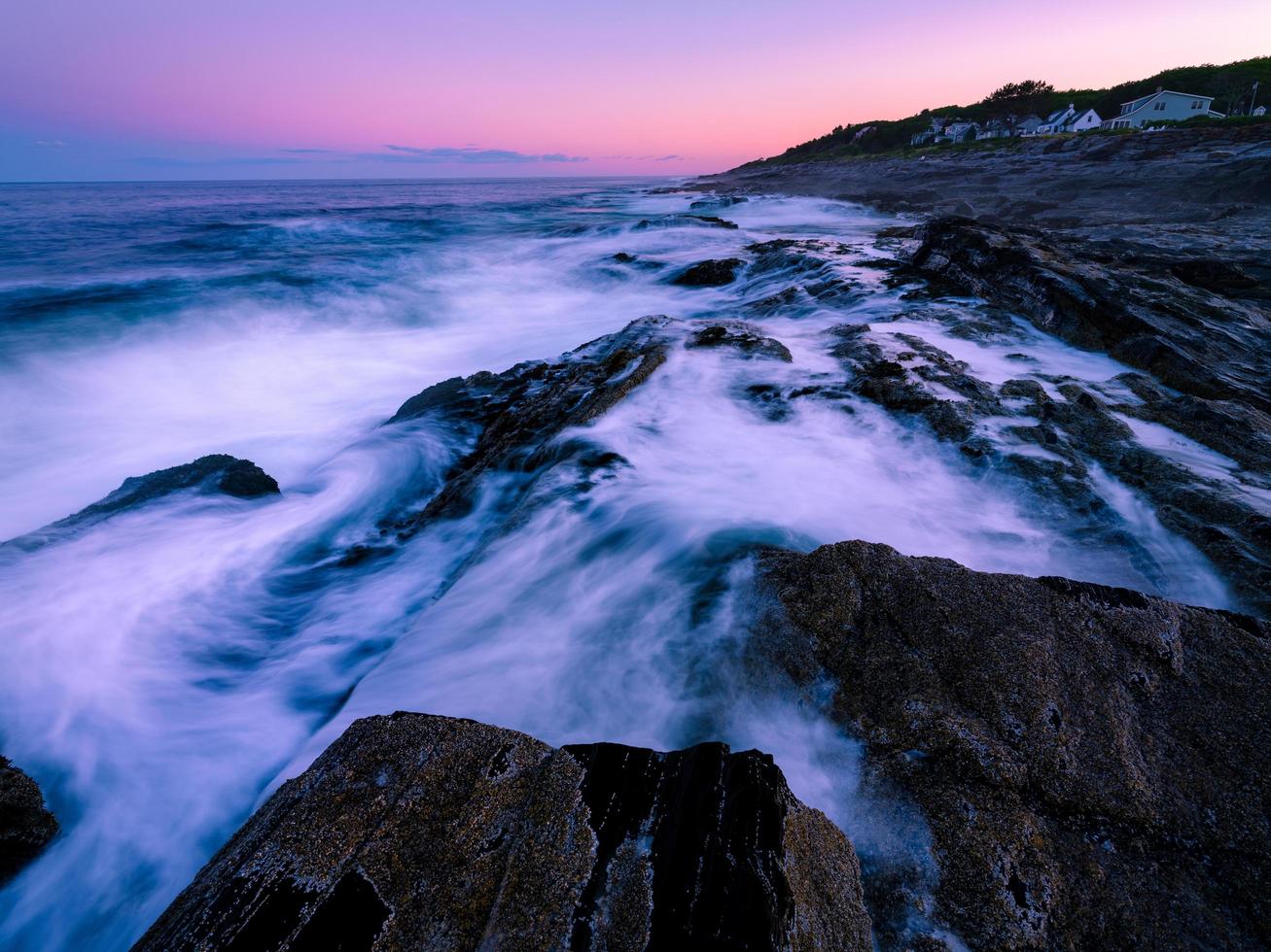 Smooth ocean wave with rock formation background photo