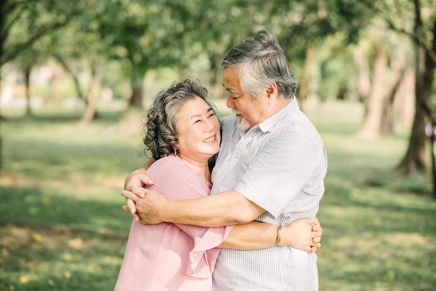 Happy senior Asian couple hugging outside photo
