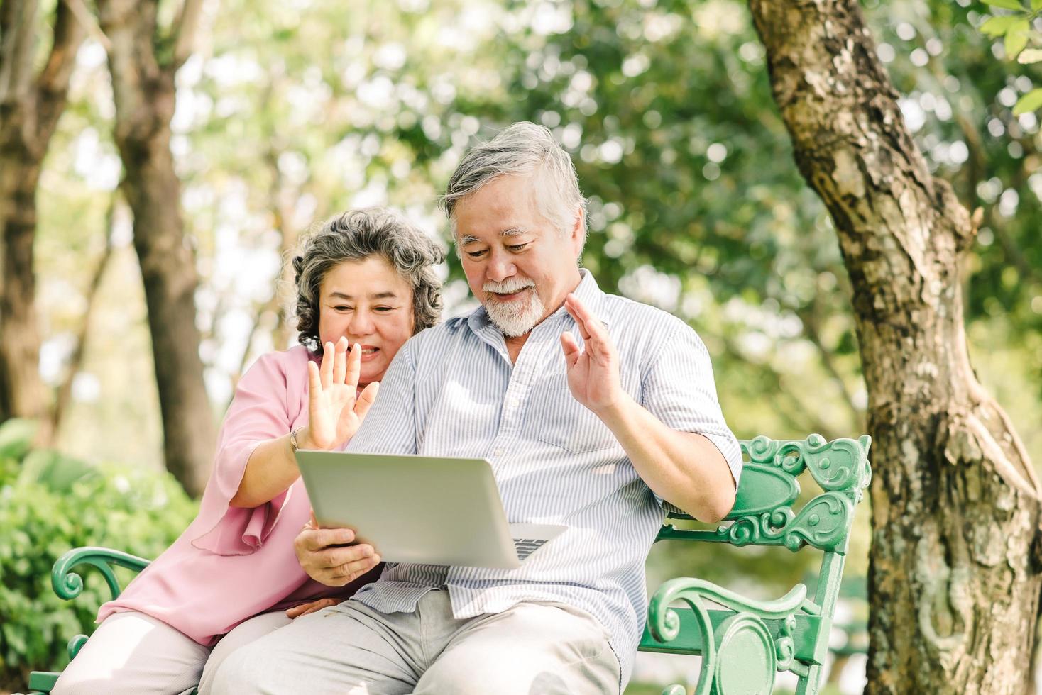 Happy senior Asian couple using laptop outside photo