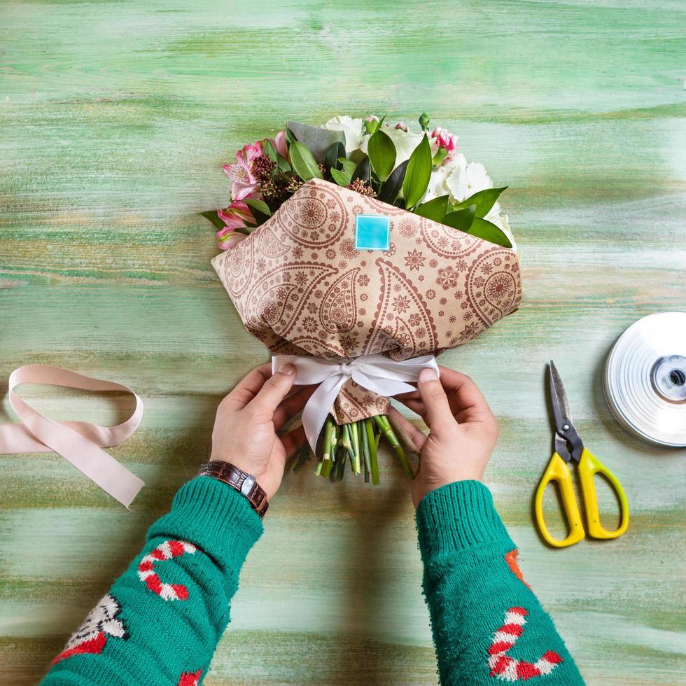 Floreria haciendo ramo de flores sobre una mesa foto