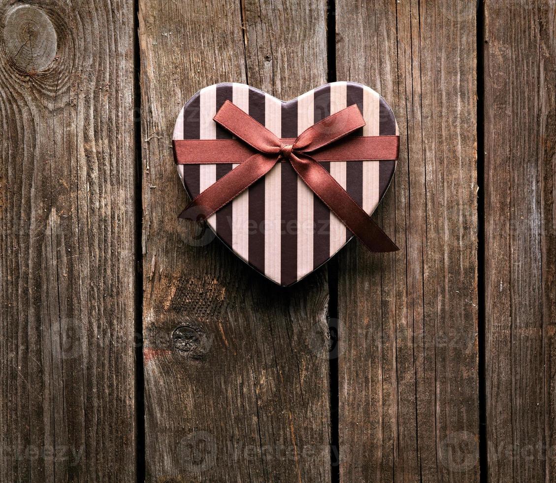 Heart-shaped Valentines Day gift box on wooden plates. photo