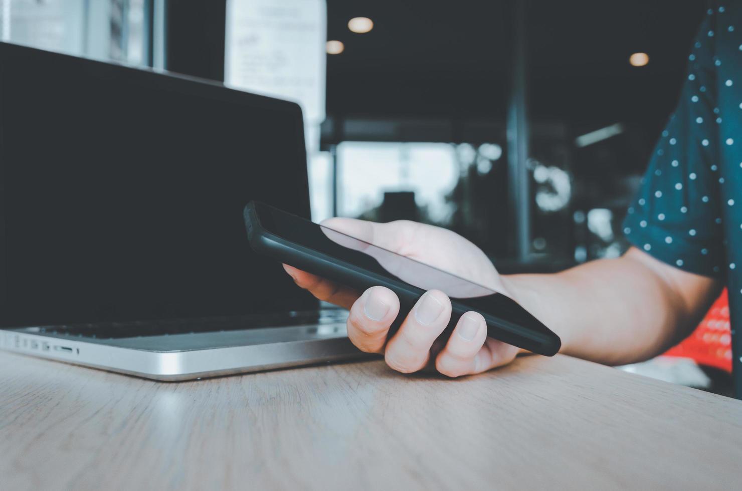 hombre sosteniendo un teléfono celular y una computadora portátil en el escritorio foto