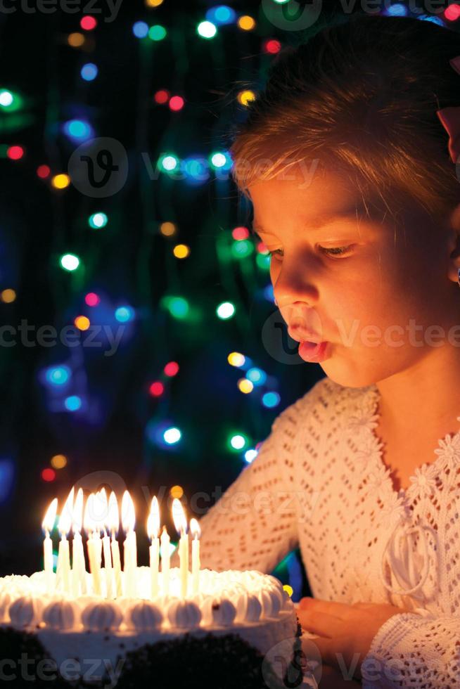 Girl blows out candles on the cake photo