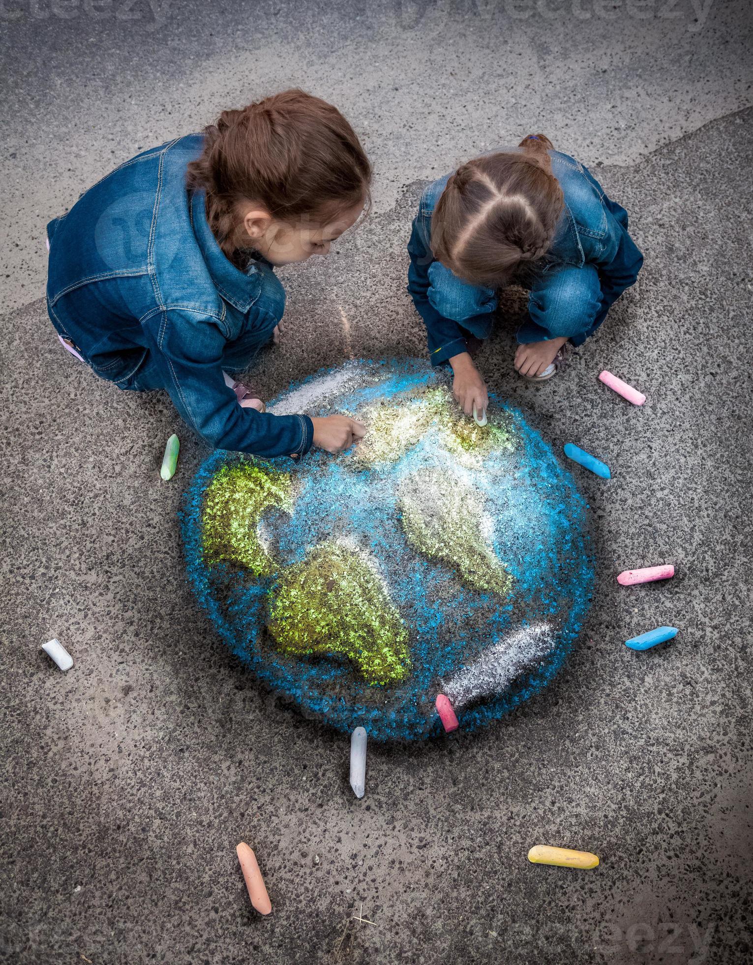 Two Girls Drawing Realistic Earth Image With Chalks On Ground Stock Photo Two Girls Drawing Realistic Earth Image With Chalks On Ground Stock Photo