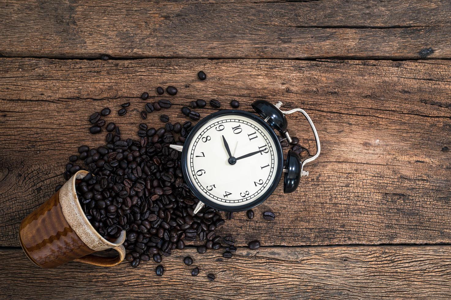 despertador y granos de café en el escritorio foto