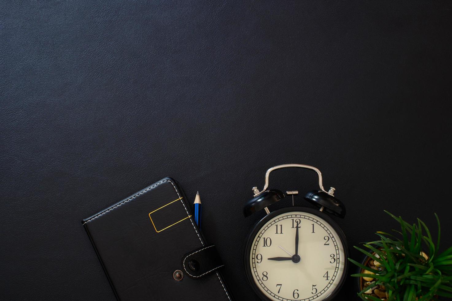 Notebook and clock on the desk, top view photo