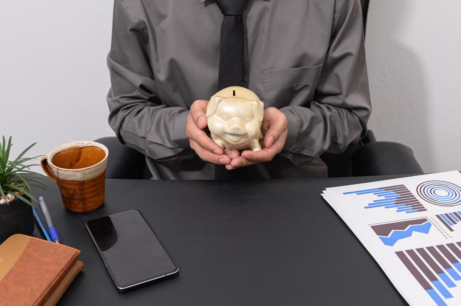 Businessman holding piggy bank at his desk photo