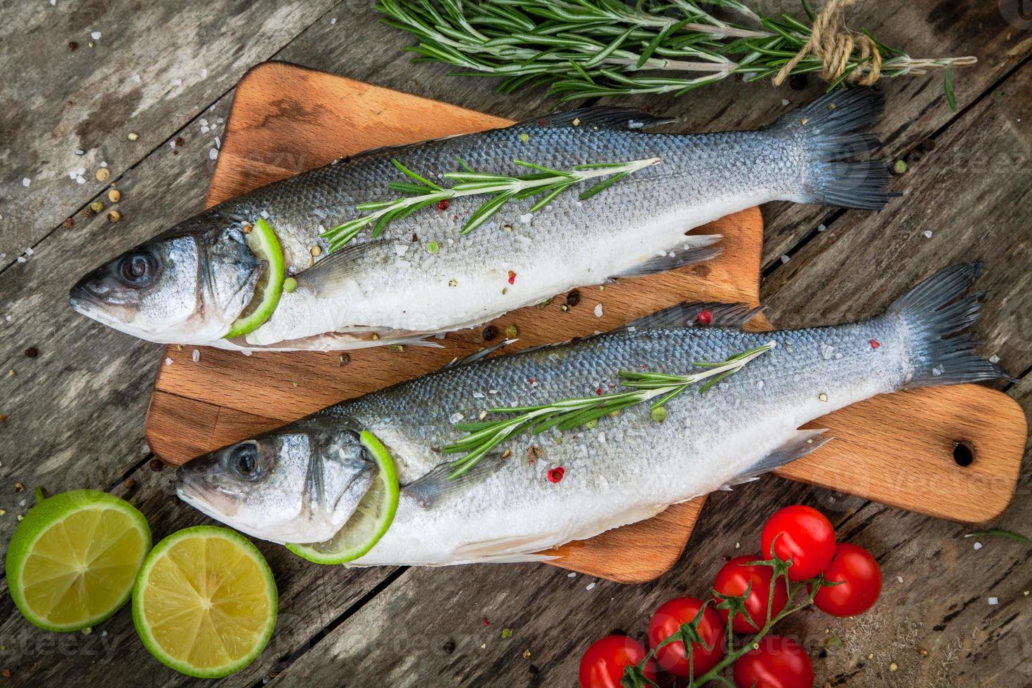 Two raw seabass with lime, cherry tomatoes and rosemary photo