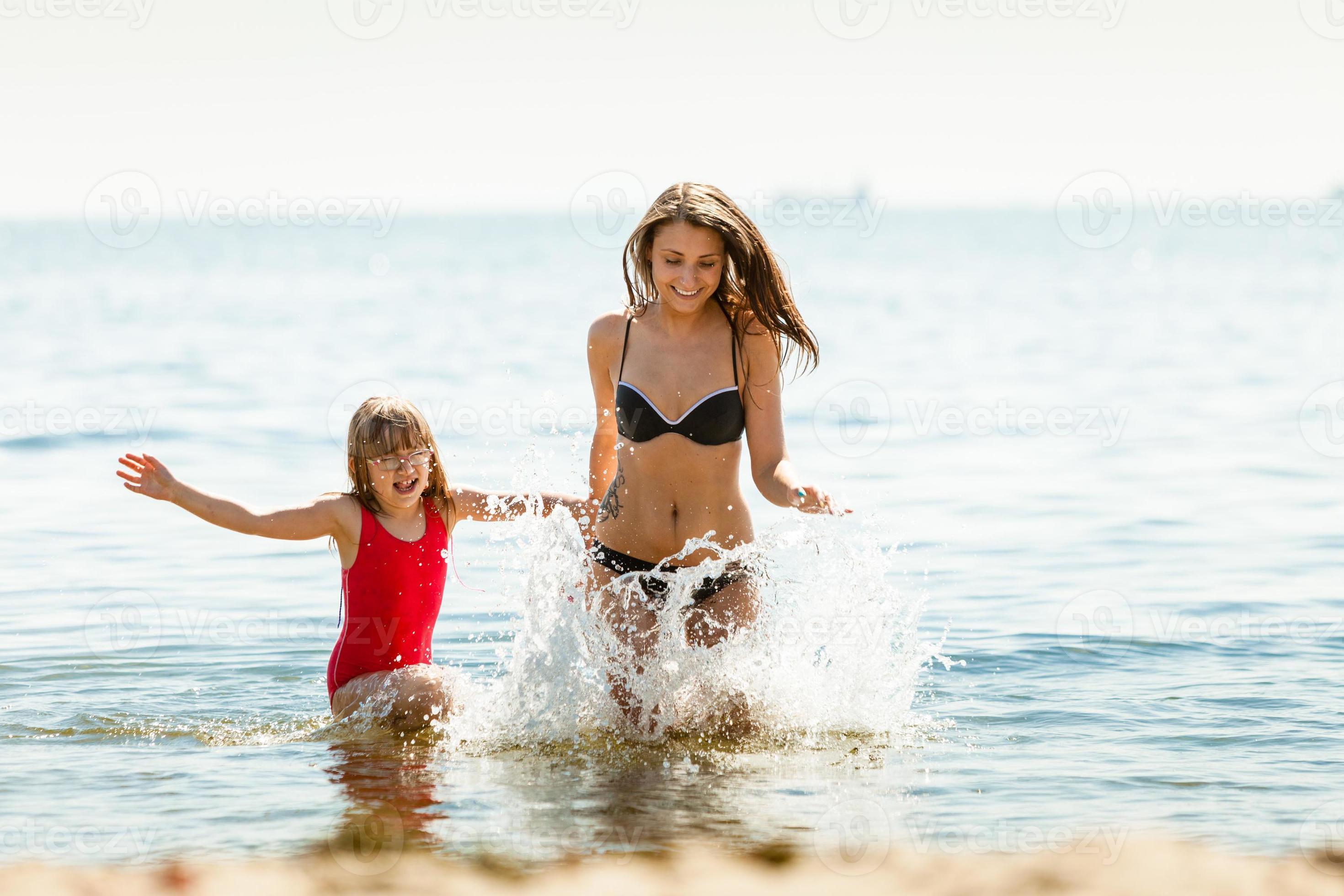 Little girl kid and woman mother in sea water. Fun photo