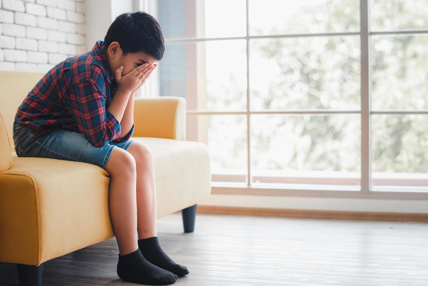 Asian boy sitting alone on sofa photo