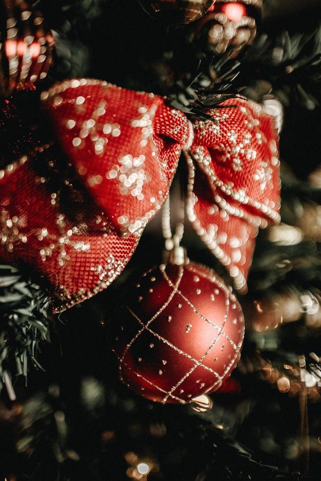 A red and gold bow hanging on a Christmas tree photo