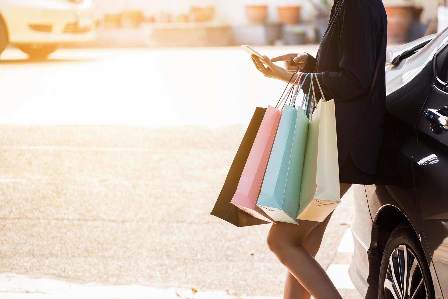 Person using smart phone holding shopping bags photo