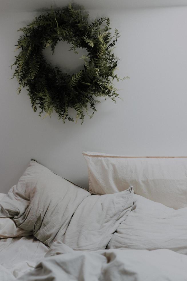 Green wreath on wall near bed photo