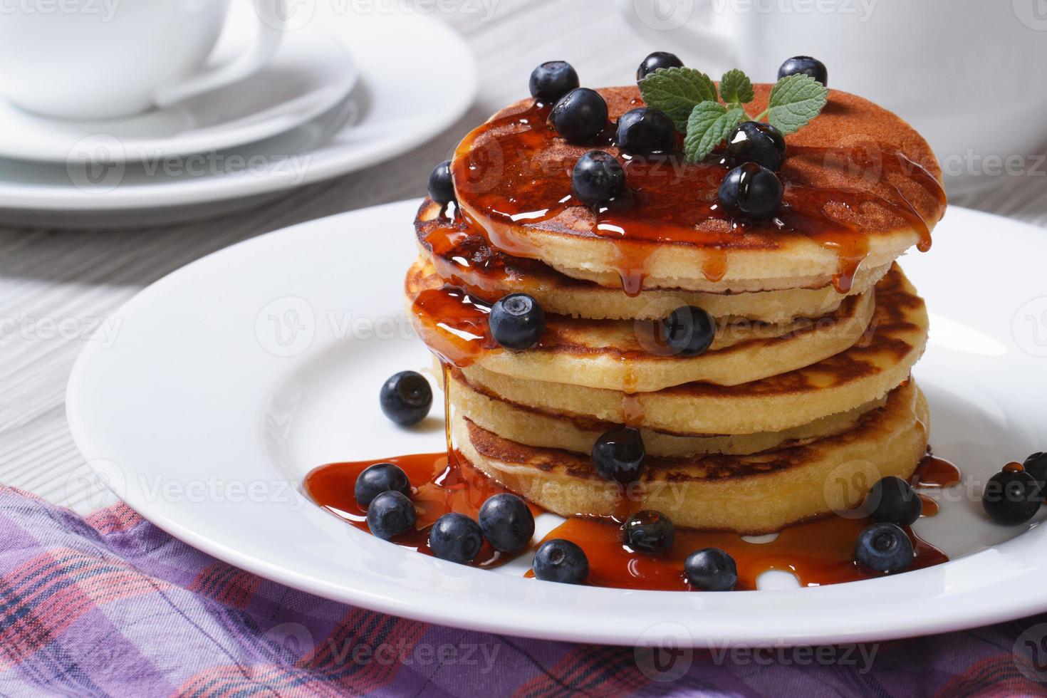 Pancake with blueberries and maple syrup on a white plate photo