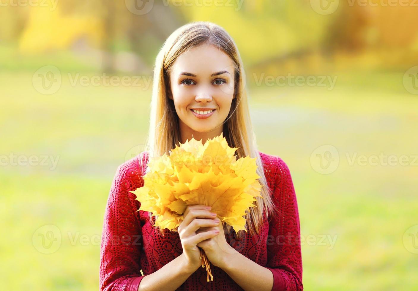 Portrait of beautiful smiling woman with yellow maple leafs autumn photo
