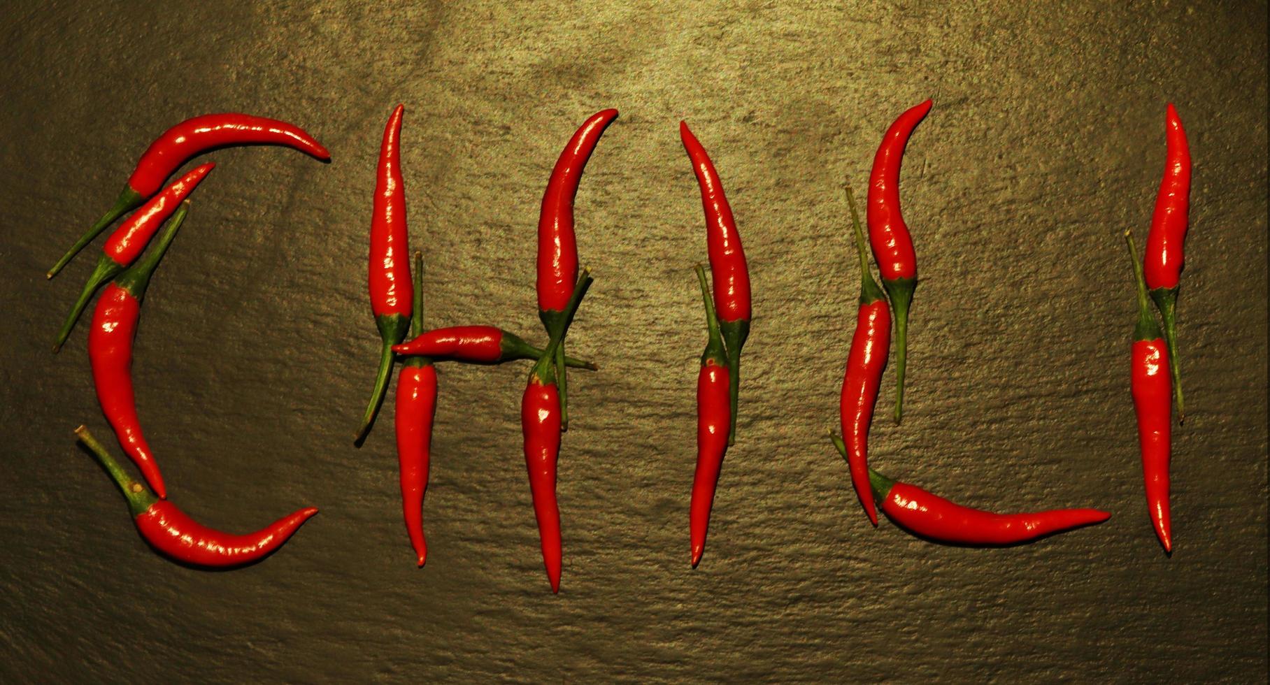 Red hot peppers spelled on slate background photo
