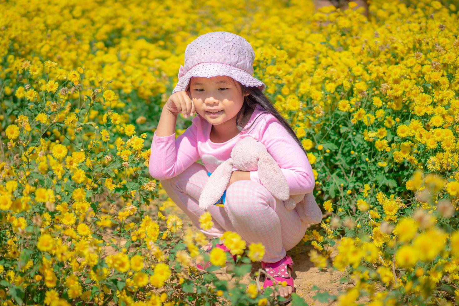 Little Asian girl in a pink dress in a flower garden photo