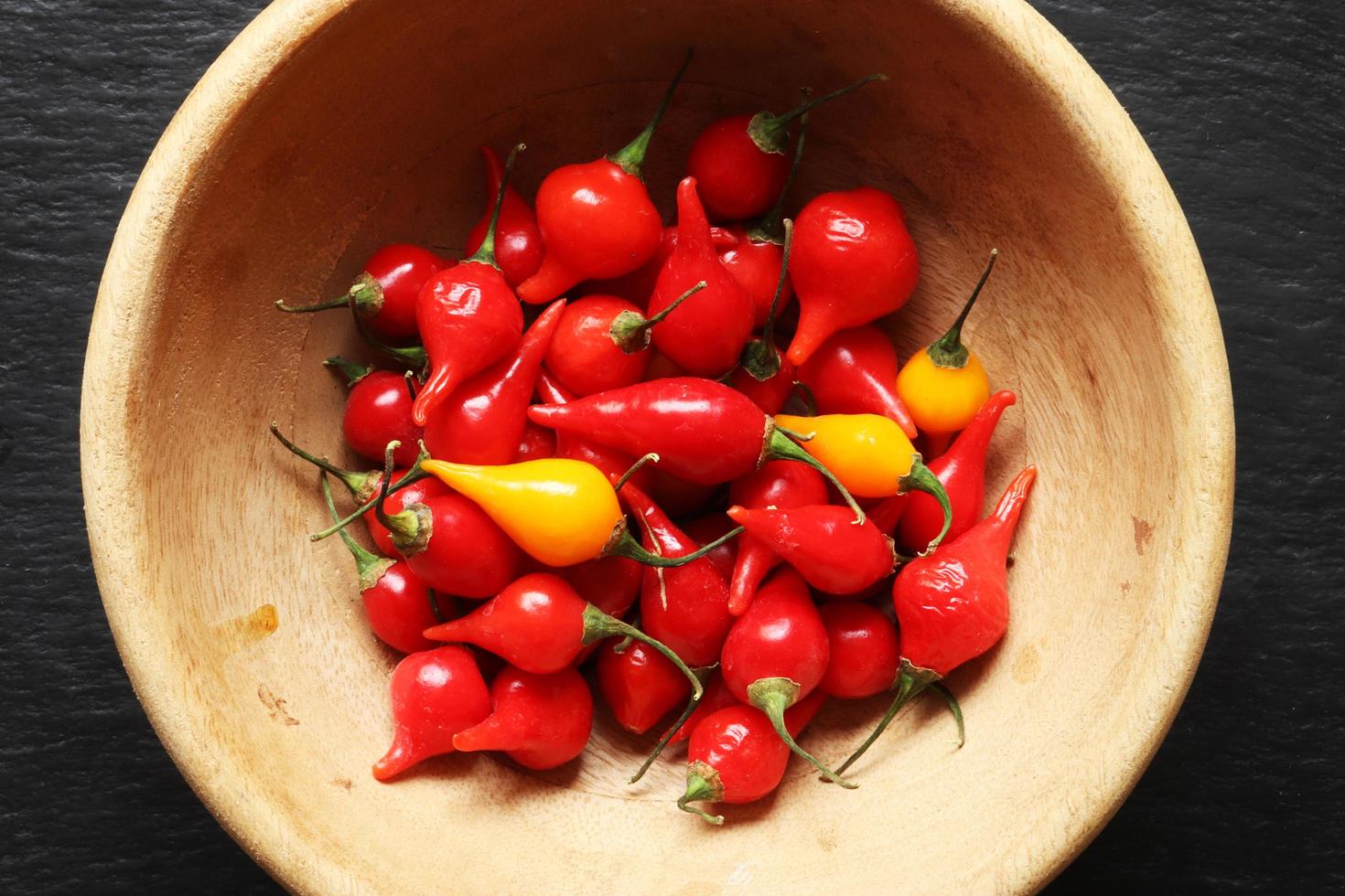 pimientos biquinhos rojos y amarillos en un cuenco de madera. foto