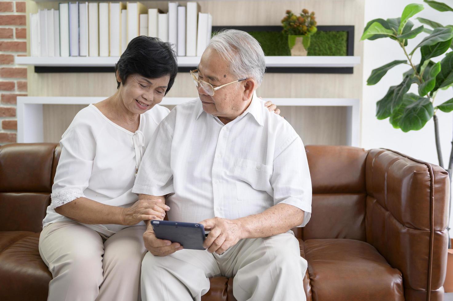 Happy senior Asian couple using tablet photo