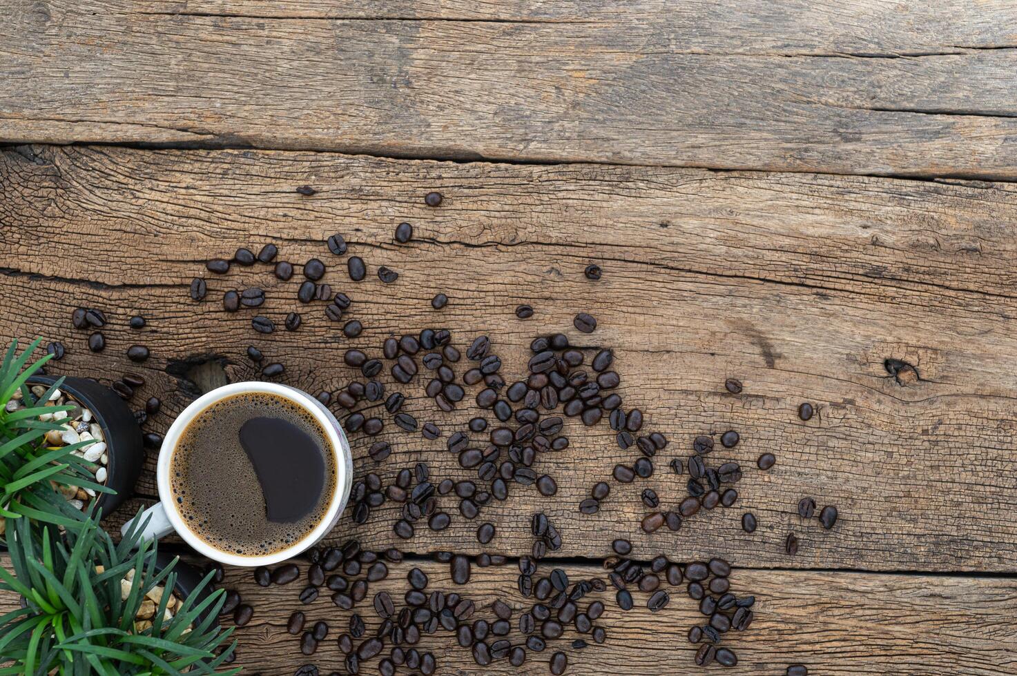 taza de café y granos de café en la mesa de madera foto