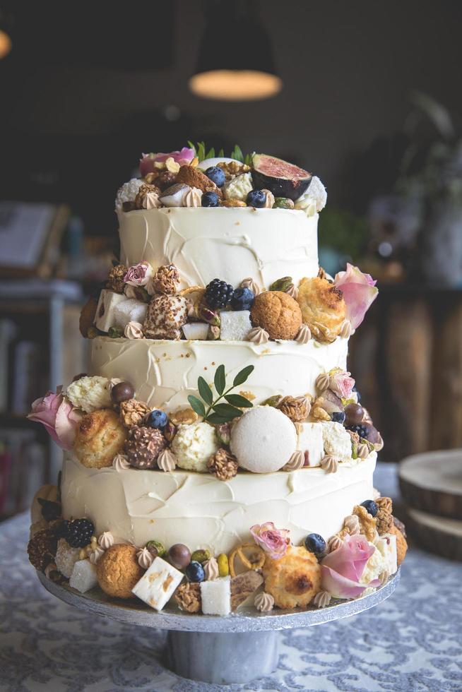 Decorative wedding cake with fruit, biscuits, macaroon and flowers photo