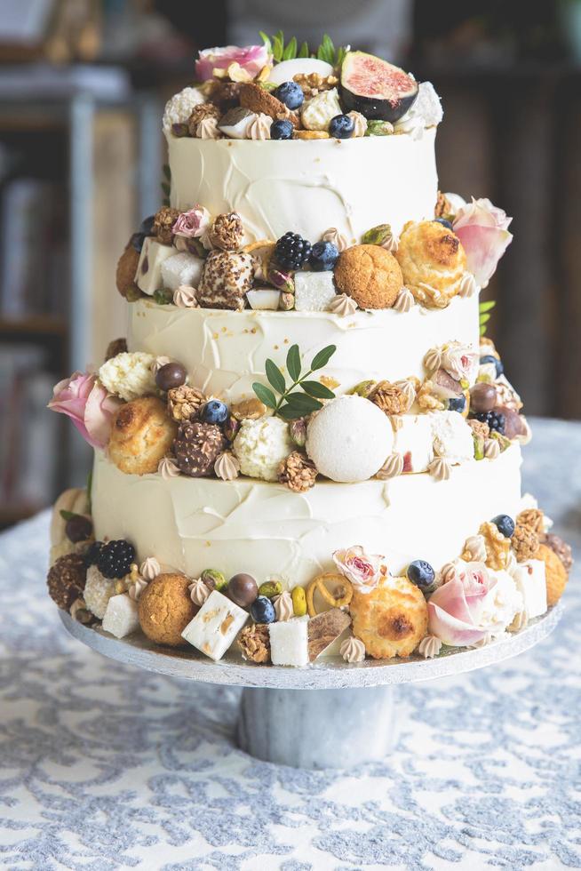 Traditional wedding cake decorated with fruits, biscuits, macaroon and flowers photo