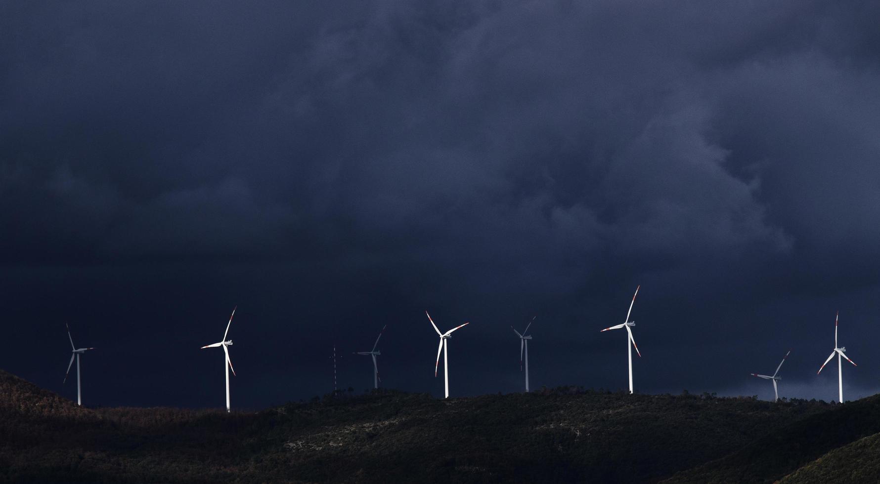 Wind turbines on hill under gray sky photo