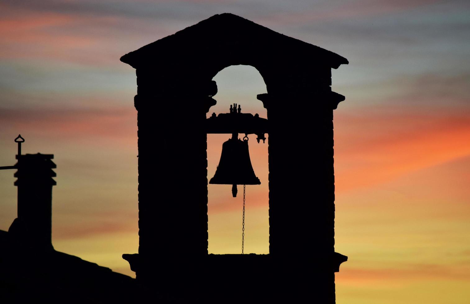 silueta de la campana de la iglesia durante la puesta de sol foto