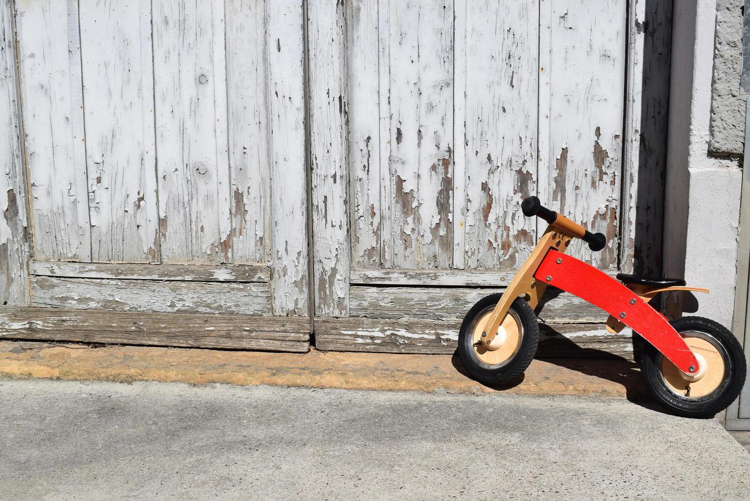 Toddler's orange bicycle park beside door photo