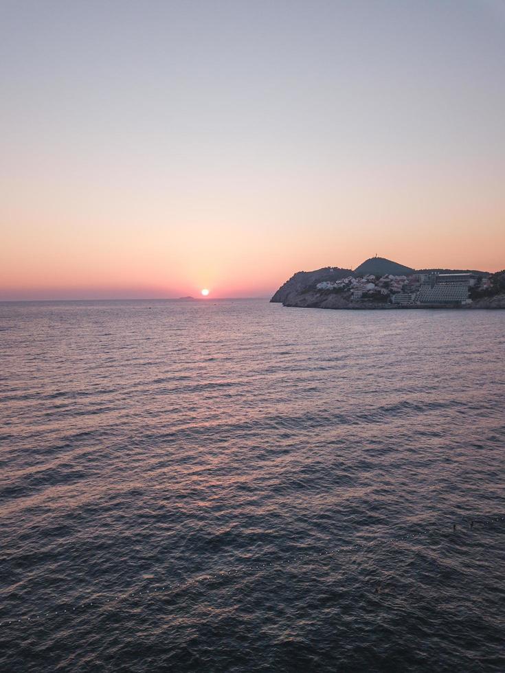 puesta de sol sobre el océano y la ciudad costera foto