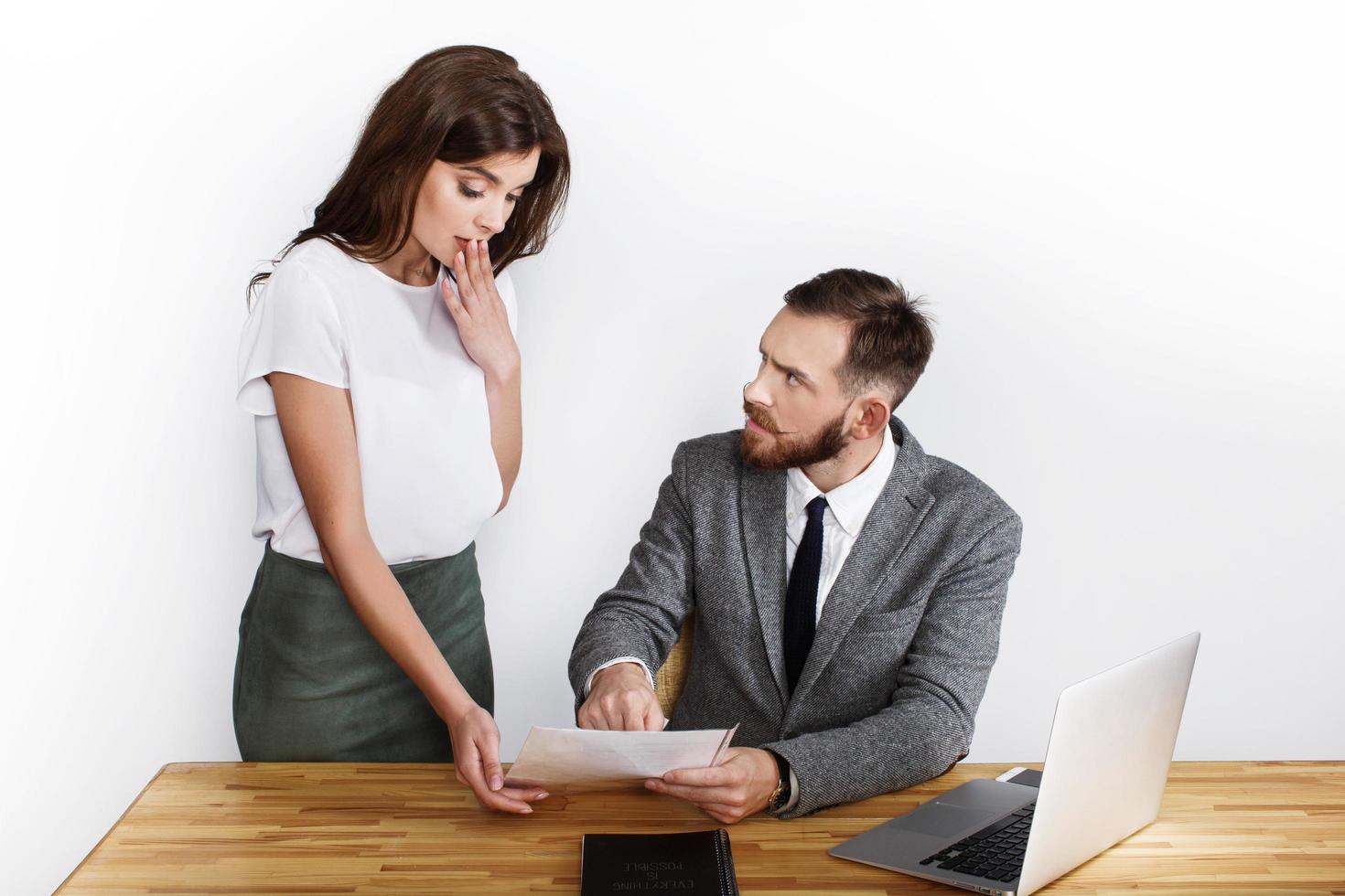 Woman looks shocked while angry businessman points to paper photo
