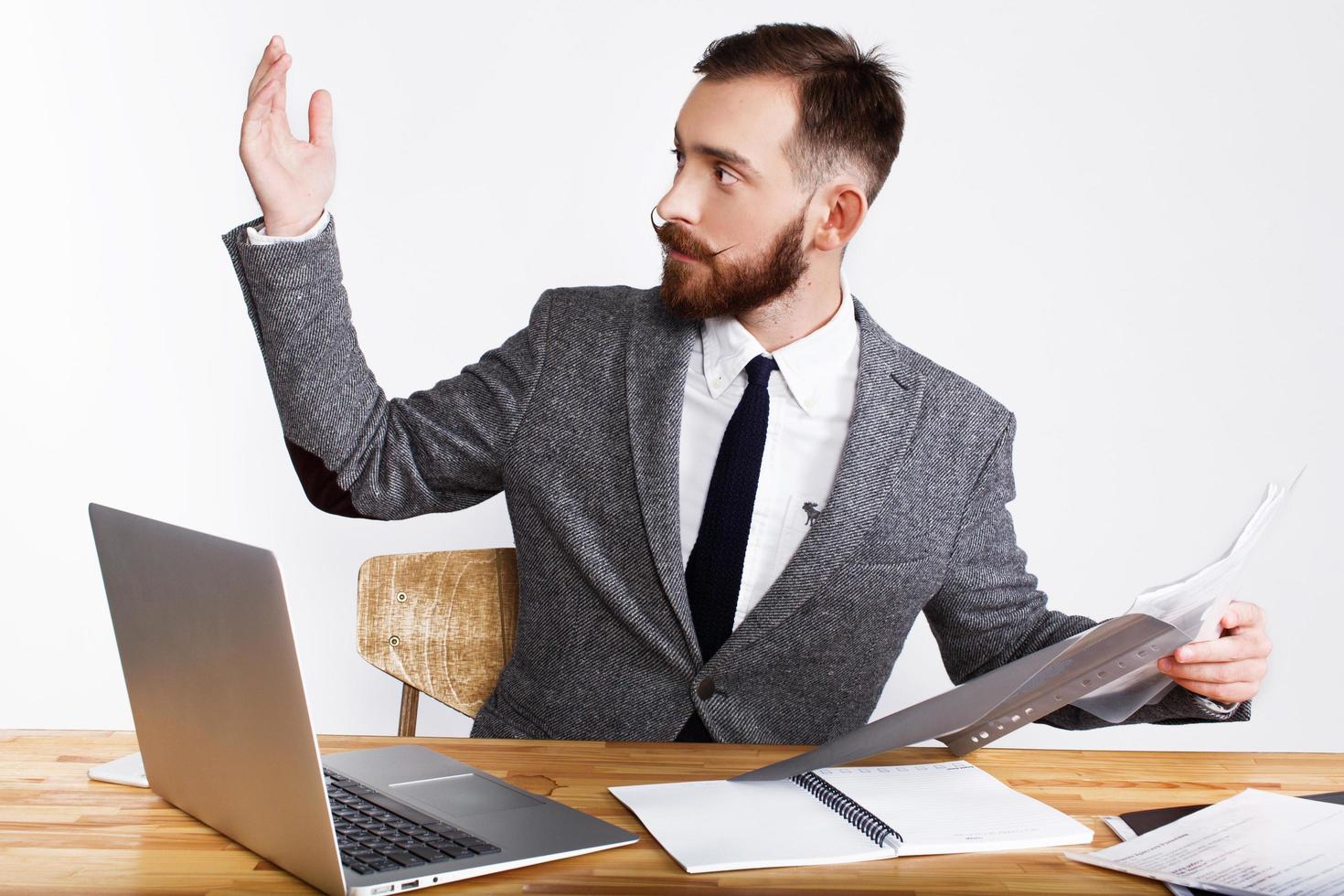 Businessman raises his hand up sitting at desk photo