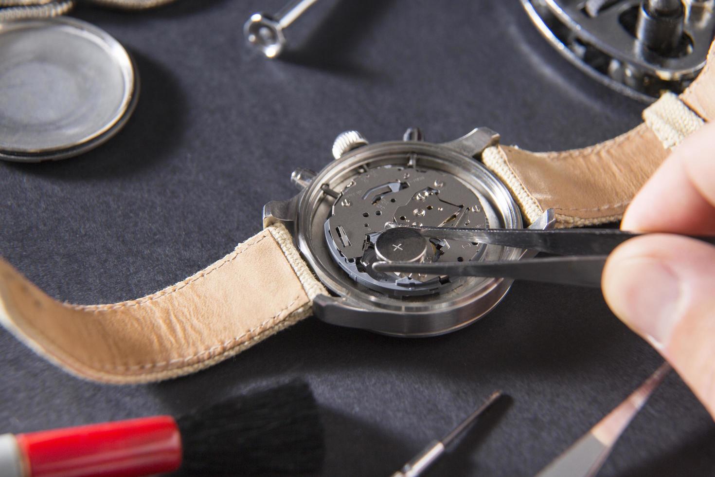 Watchmaker using tweezers on watch photo