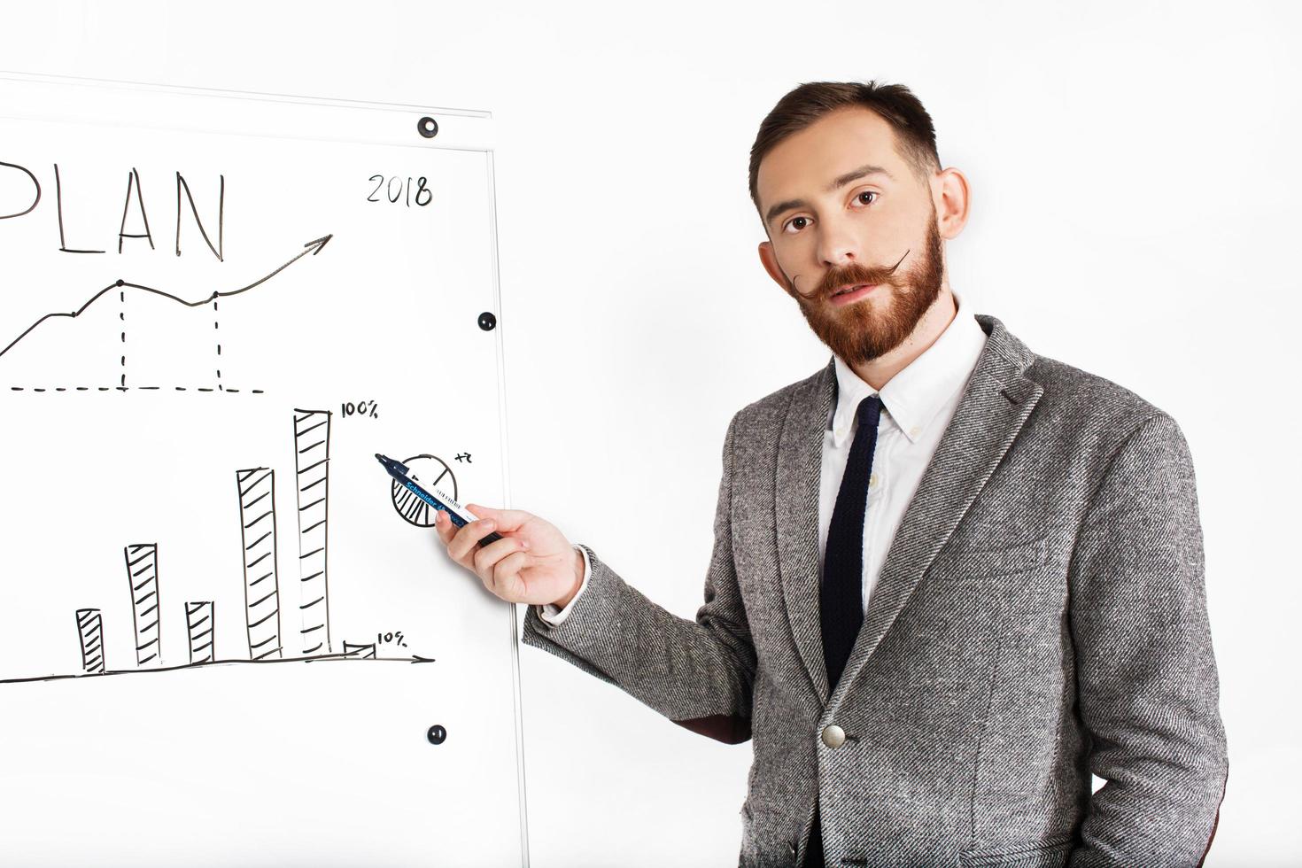 Man dressed in office suit writes on graph on a white background photo