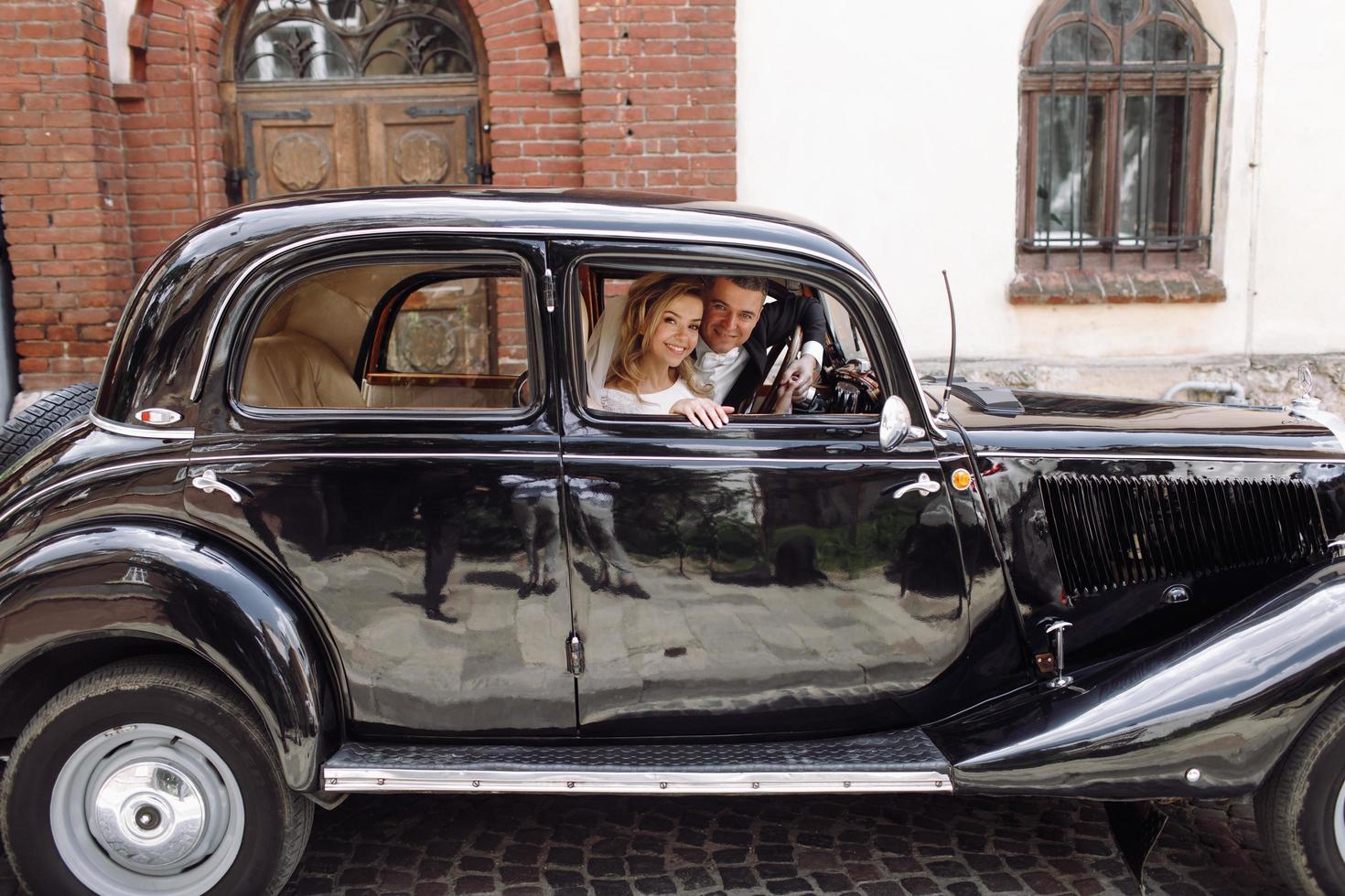 Classy wedding couple smiles in retro car photo