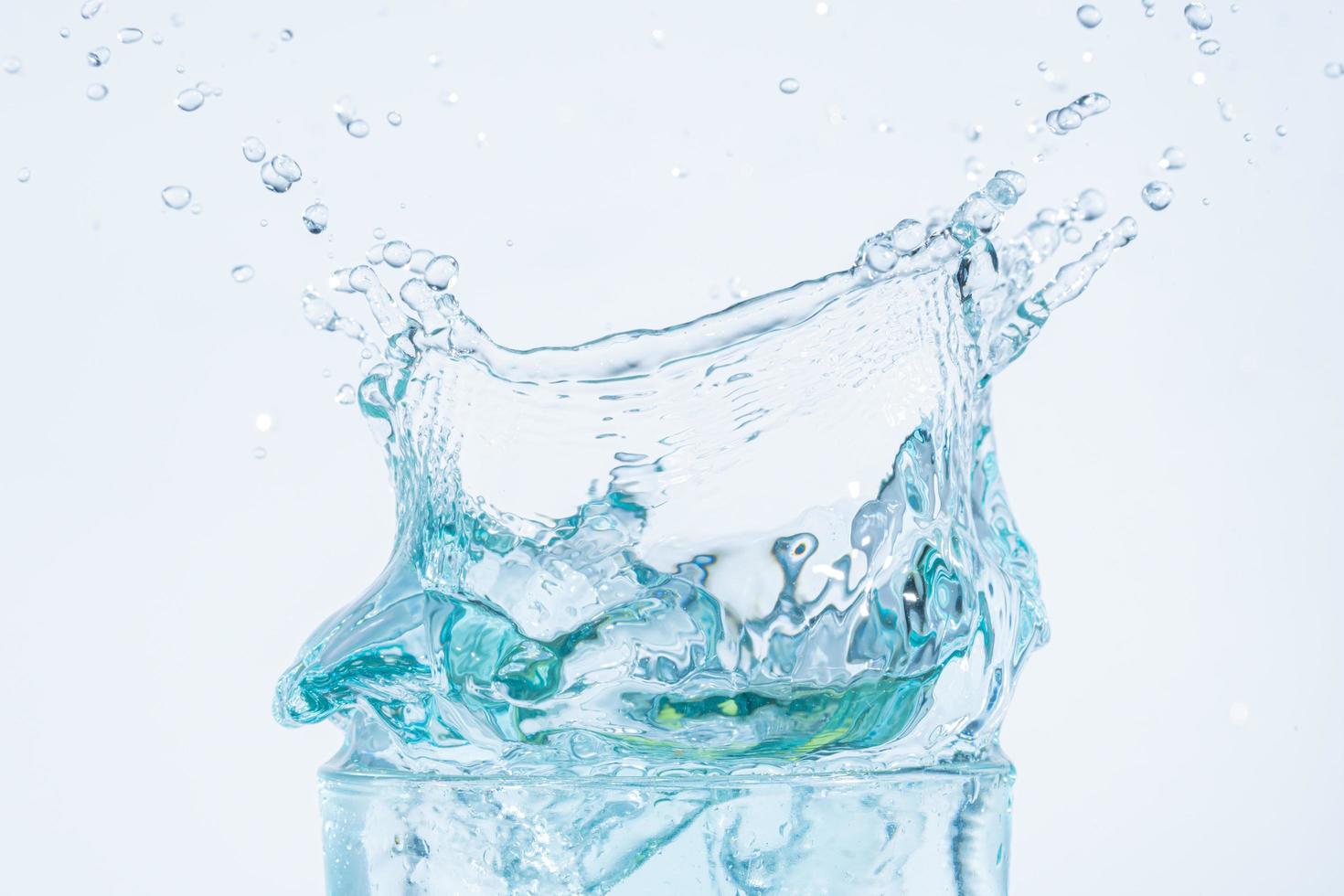 Salpicaduras de agua en un vaso de fondo blanco. foto