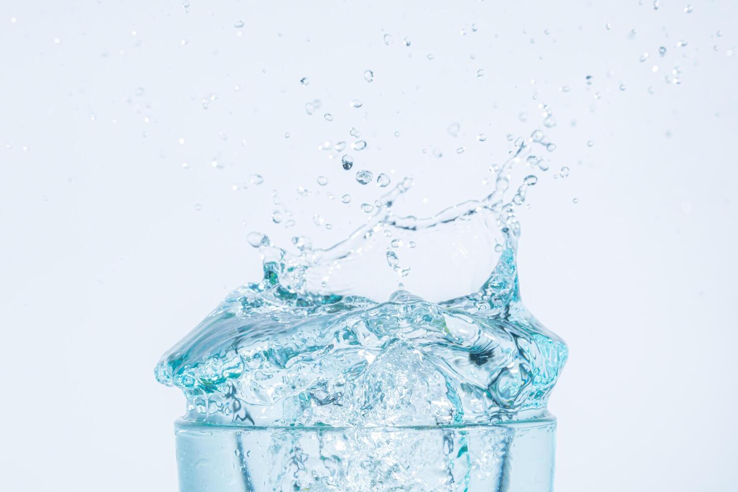 Salpicaduras de agua en un vaso sobre fondo blanco. foto